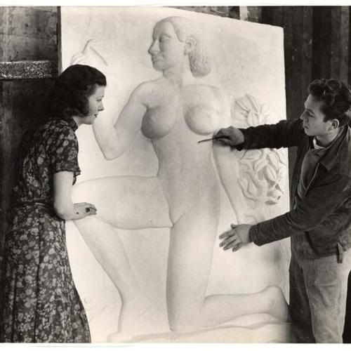 [Sculptor David Slivka working on the clay model for bas relief "Fertility" as Mildred Clausen looks on, Golden Gate International Exposition on Treasure Island]