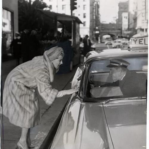 [Lana Turner talking to taxi driver as part of a scene during the shooting of the motion picture "Portrait in Black"]