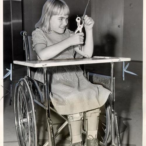 [Girl at Shriners' Hospital for Crippled Children making a present for football players in the East-West Shrine game]