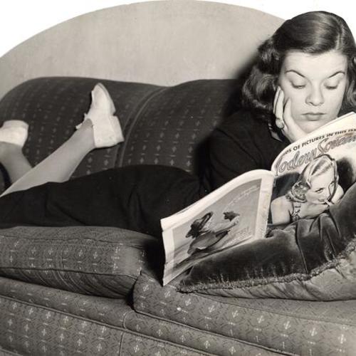 [Unemployed young woman reading a movie magazine]