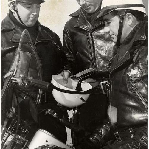 [Police officers examining new plastic crash helmets]