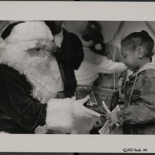 Child receiving gift from Santa Claus at Boeddeker Park Christmas party
