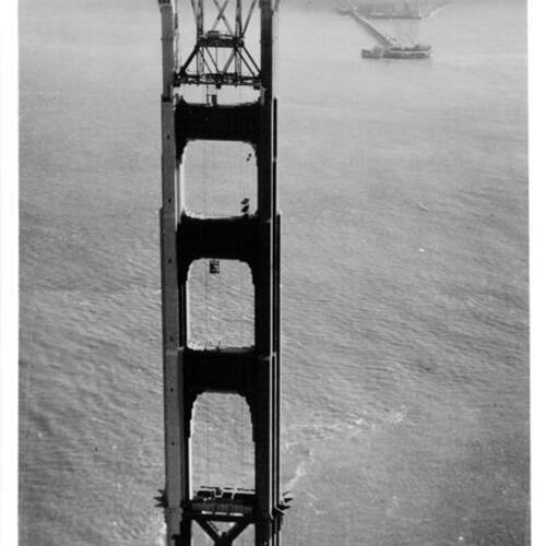 [Aerial view of Marin tower of Golden Gate Bridge under construction with fog shrouded San Francisco in background]