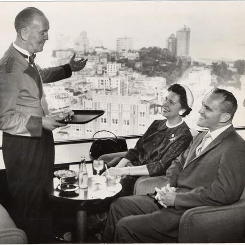 [Waiter Barney Healy of the Top of the Mark restaurant talking with two customers]