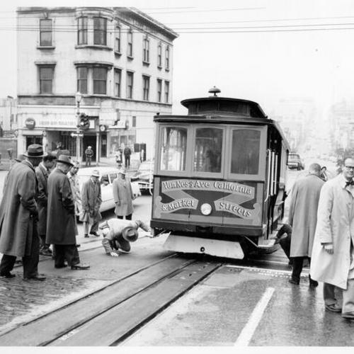 [Group of people gathered around a cable car at California and Hyde streets]