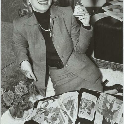 Patricia Sheenan with newspaper clippings and photos while holding up her Miss California trophy