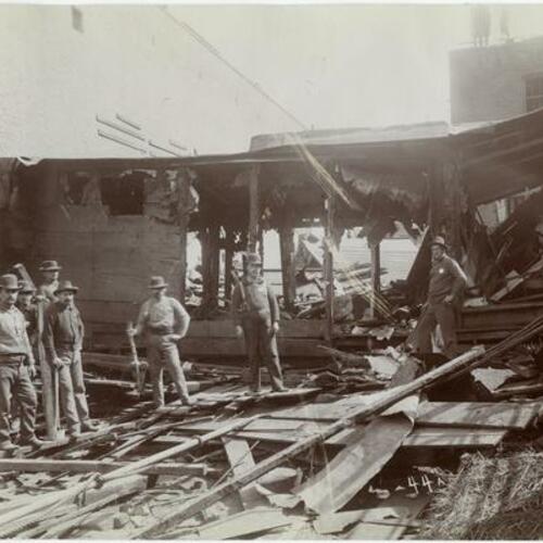 044 People with axes standing in debris of wooden buildings during demolition