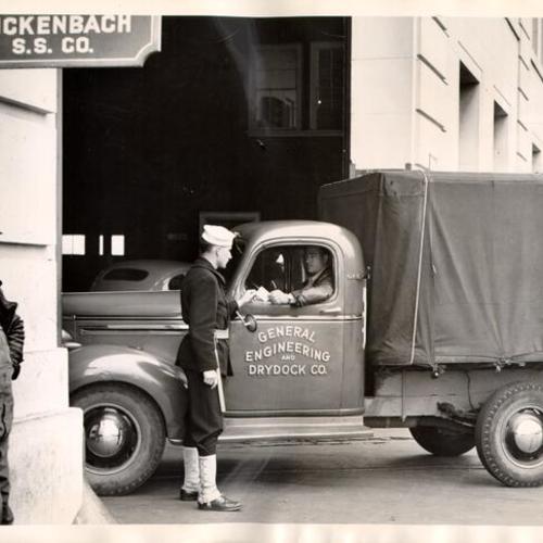 [Coast Guardsman checking the identification card of a truck driver at the San Francisco waterfront]