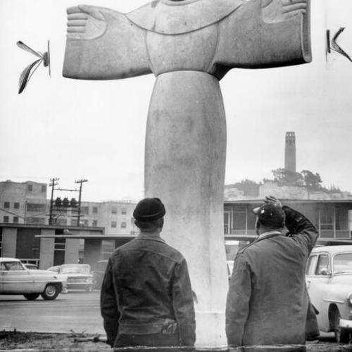 [Two unidentified people standing next to the statue of Saint Francis of Assisi on the grounds of the ILWU building at Fisherman's Wharf]