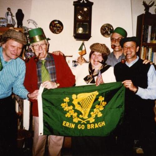 [Friends posing with pipes at a Saint Patrick's Day party holding a flag that says, "Erin go bragh"]