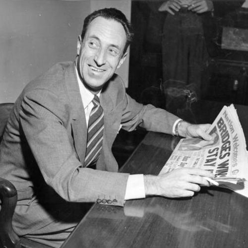 [Harry Bridges, smiling as he reads headlines that his deportation order was invalid]