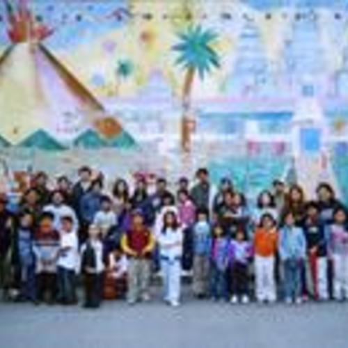 [Filipino Education Center Galing Bata staff, parents, and students in the school yard by the mural]