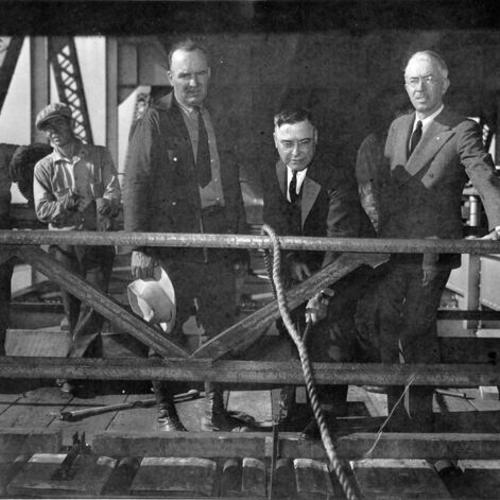 [Charles E. Andrew putting the first redwood tie into place for the San Francisco-Oakland Bay Bridge electric railway system]
