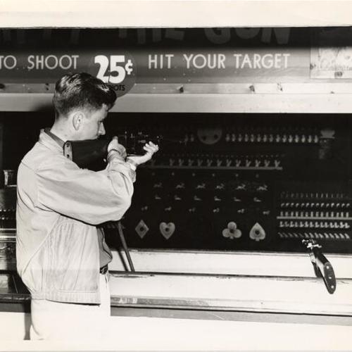 [Young man playing a target shooting game at Playland at the Beach]