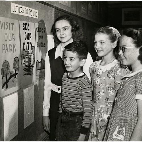 [Sixth grade students looking over posters urging United Nations Organization to establish headquarters in San Francisco]