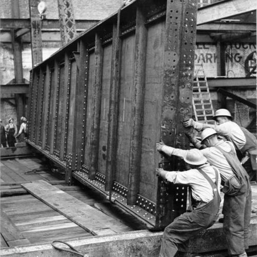 [Bethlehem Pacific erection crew placing a 28-ton girder during construction of Macy's department store on O'Farrell Street]