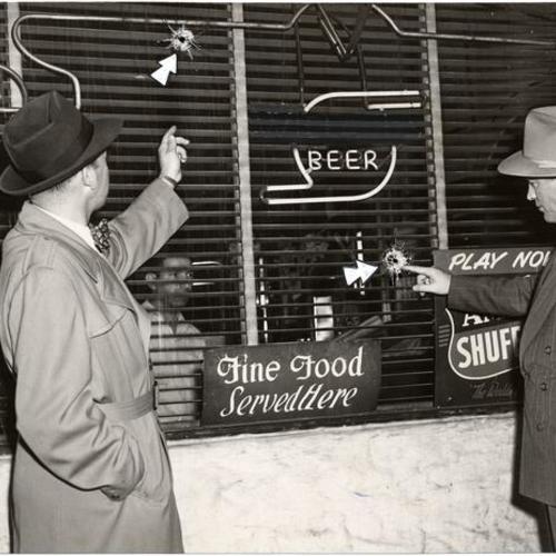 [Police Inspectors Al Nelder and Edward Van der Vort examining the bullet-punctured front of a tavern at Fifth and Howard streets]