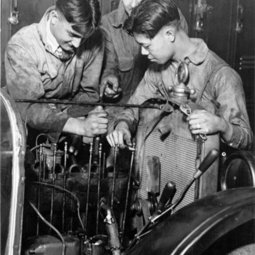 [Three unidentified people working on an automobile at Mission High School]