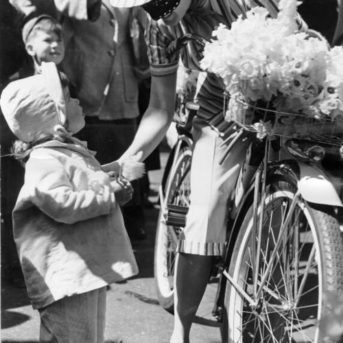 [Two year old Christina Huth receiving a daffodil from the "Mystery Mannequin" at the Maiden Lane Festival]