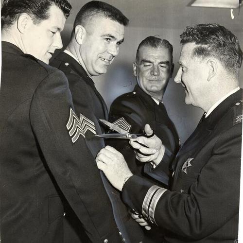 [Police Chief Thomas Cahill removing the stripes from Mortimer McInerny, Eugene S. Caldwell and Frank J. Browne before presenting them with bars]
