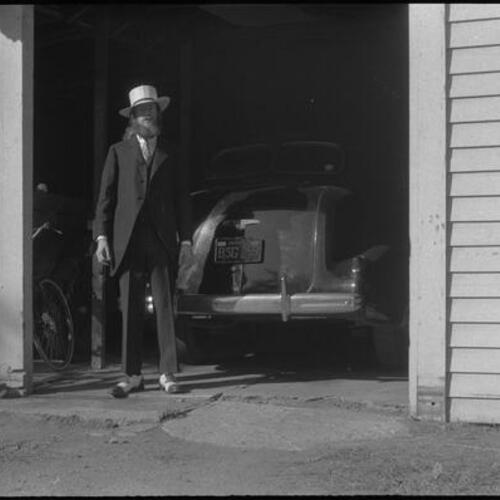 Stuart Jenkins in Panama hat and suit standing outside in front of car, Mountain View