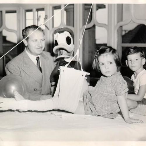 [Man with a Donald Duck doll visiting patients at the Shriners' Hospital for Crippled Children]