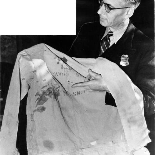 [Bailiff Walter Beram holding the bloodstained shirt of convict Milton Pettijohn, during a trial of two other prisoners who made a failed escape attempt from Alcatraz Prison in May, 1938]