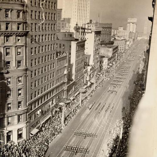[Crowd of spectators watching parade marching down the street, celebrating opening day of the San Francisco-Oakland Bay Bridge]