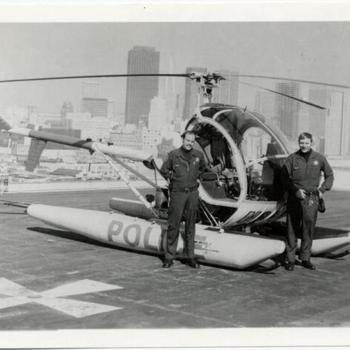 [Two policemen standing next to San Francisco Police Department helicopter]