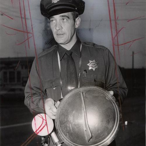 [Patrolman George J. Steigler holding a hub cap]