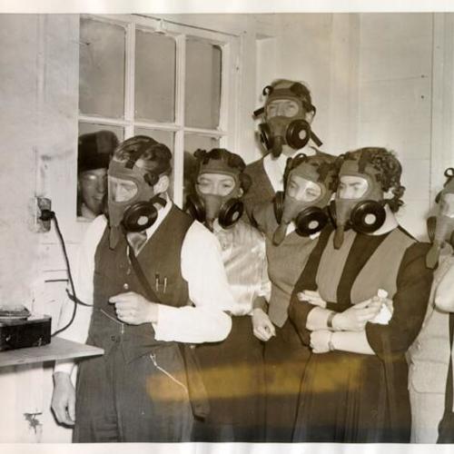 [Commander L. E. Clifford demonstrating the use of gas masks to a group of civilian employees at the Yerba Buena Island naval training station]
