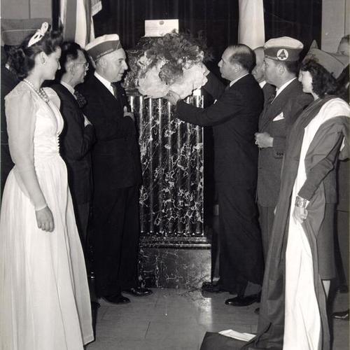 [Legionnaires and members of San Francisco French Colony placing decorations on the memorial to the Unknown Soldier in the Veterans' War Memorial Building]