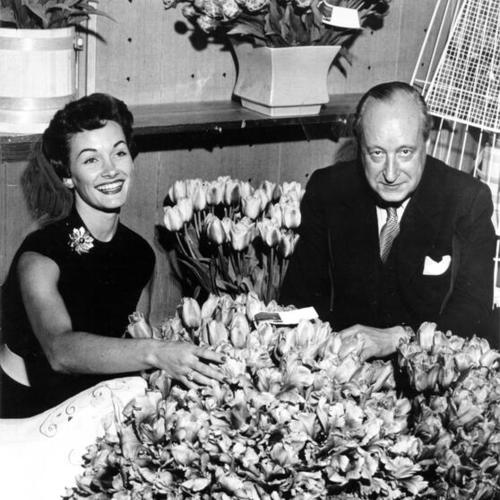[Macy's employee Betty Farrar and Netherlands Consul General Willem van Tets posing with a display of tulips from the Netherlands]