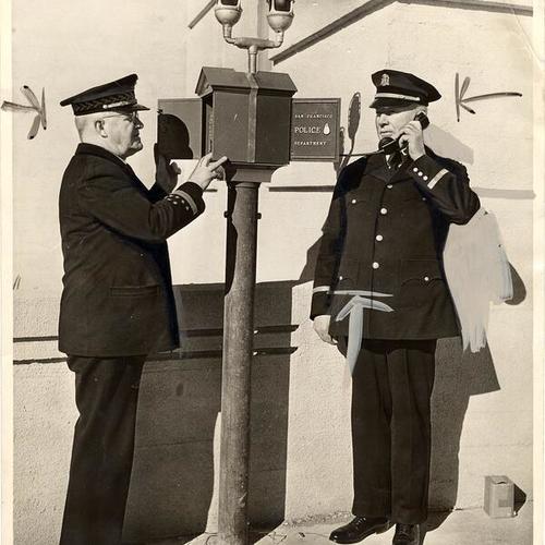 [Officers Chas. J. Brennan and John J. O'Meara using the street police telephone]