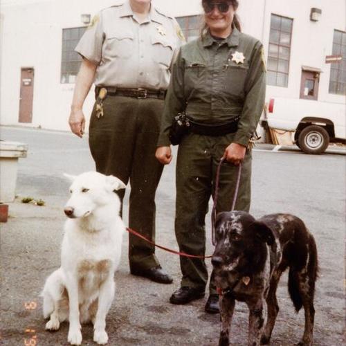 [First female Golden Gate Park Patrol Officer holding two canines with male supervisor]