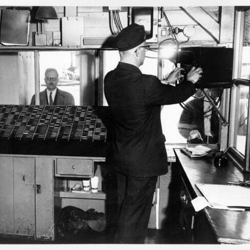 [Unidentified guard operating the "snitch box" at the registration desk on Alcatraz]