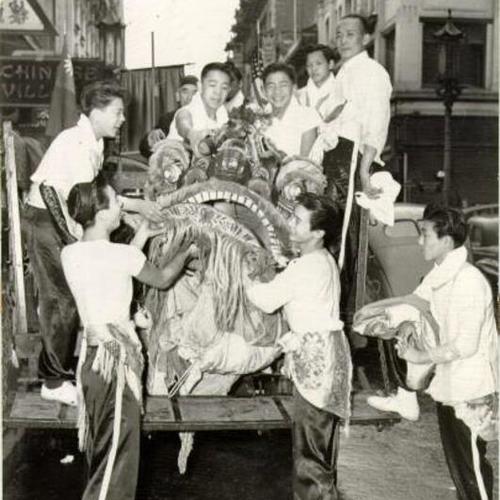 [Boys of the Gan Min Club unloading Sze Sze, the Magnificent Lion, from a truck in preparation for the Chinese New Year celebration]