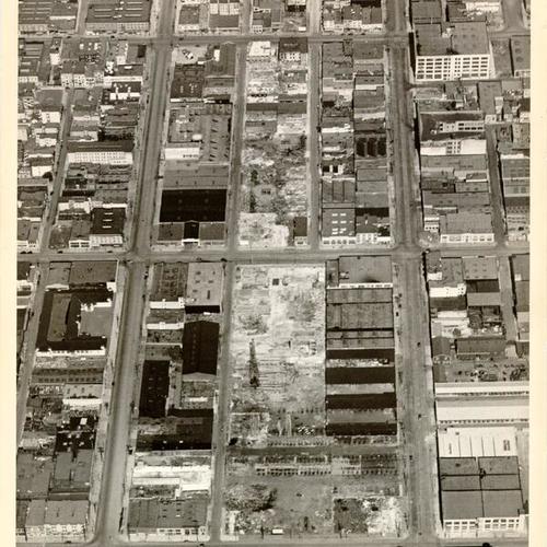 [Aerial view of path of demolished buildings along San Francisco Bay Bridge approach and construction of concrete piles]