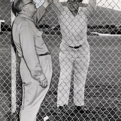[Floyd Guffin and James McKay standing on opposite sides of a fence at Sharp Park Golf Course]