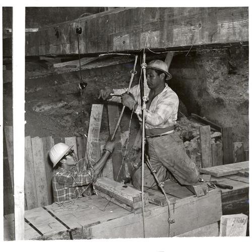 [Workers lowering cable duct at the construction site of Pacific Telephone and Telegraph Company building on Pine Street]