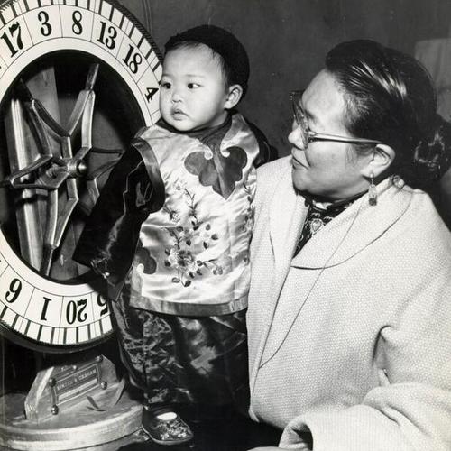 [Woman and child standing next to novelty wheel]