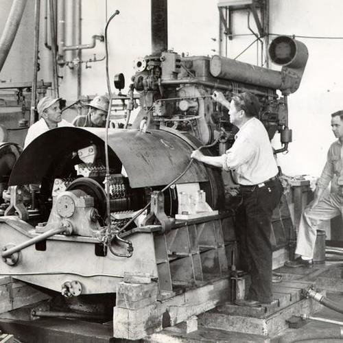 [Workers working on a cruiser diesel engine]