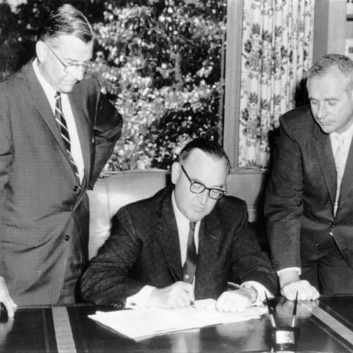 [Governor Edmund G. Brown signs a bill committing the state to construction of a 115 million-dollar trans-bay underwater rapid transit tube linking San Francisco and Oakland]