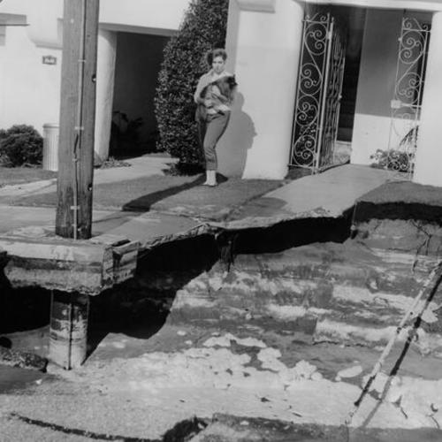 [Lynette Cameron inspecting the damage done to her home, at 2524 Rivera Street, by a broken water main]