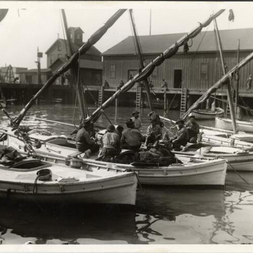 [Several men sitting on boats docked in the Fisherman's Wharf]