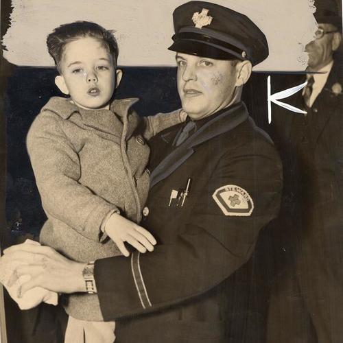 [Officer Douglas McMillan holding a boy in his arms]