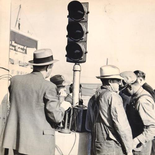 [Men waiting around the signal light for President Roosevelt's indication to open San Francisco-Oakland Bay Bridge]