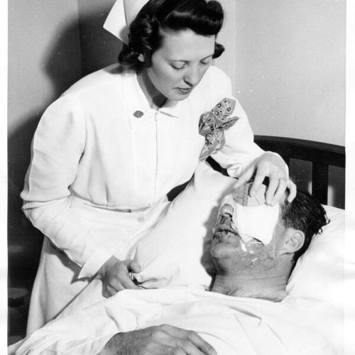[Nurse Isabelle Shepphird holding bandage over the eye of Frank "Lefty" O'Doul]