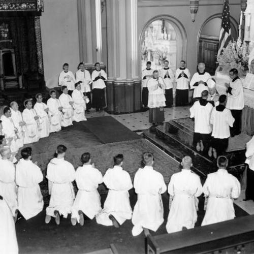 [Twenty men kneeling for ordination as new priests in Old St. Mary's Cathedral]