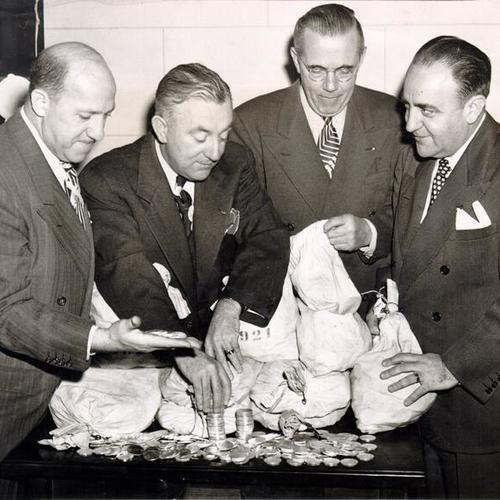 [George Edelstein, George Gillen, A. F. Buckman and Joseph S. Ravinsky looking at 10,000 silver dollars at the 16th and Mission branch of Bank of America]
